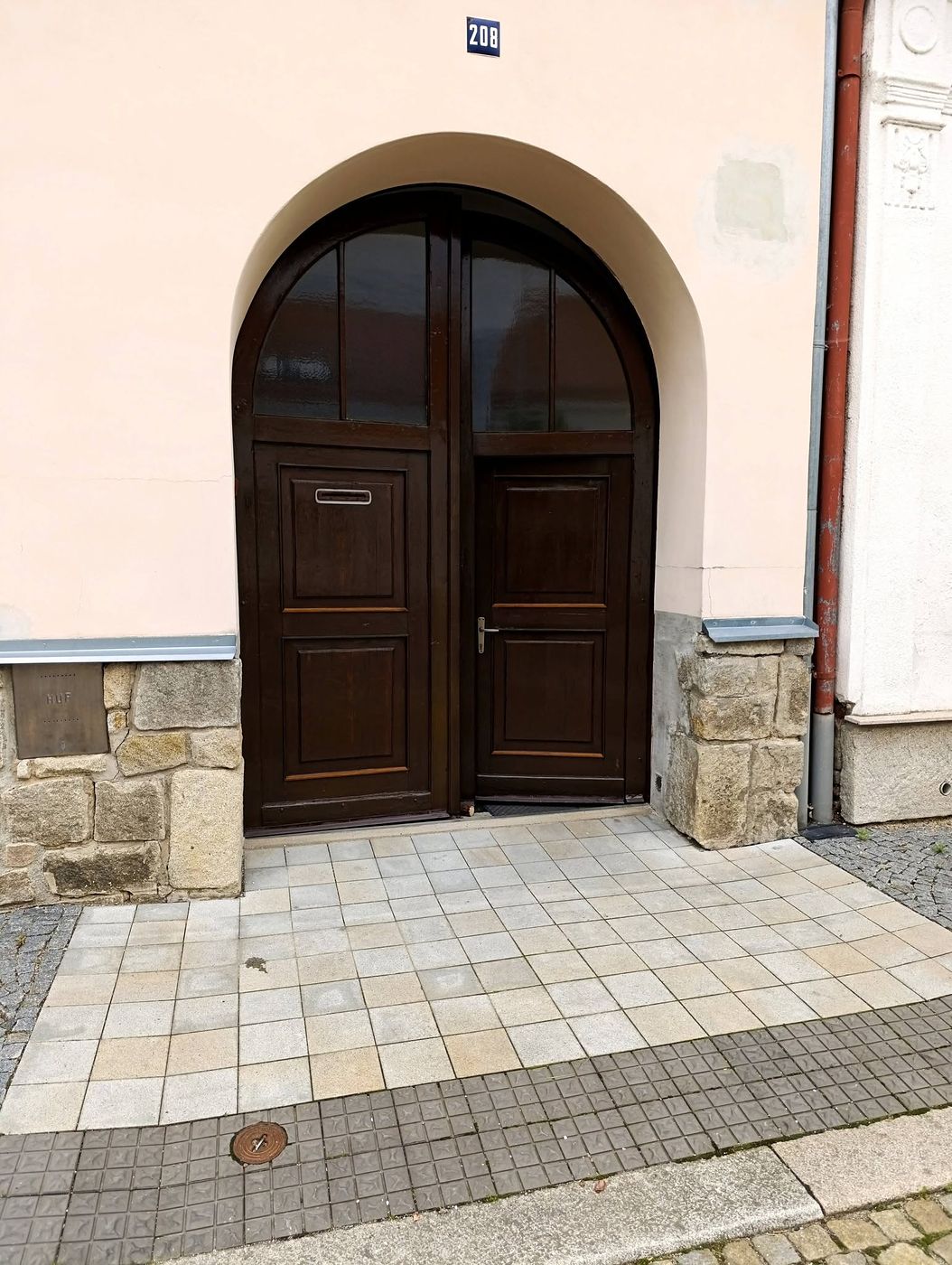 Vstupní dřevěné dveře v oblouku světlé fasády