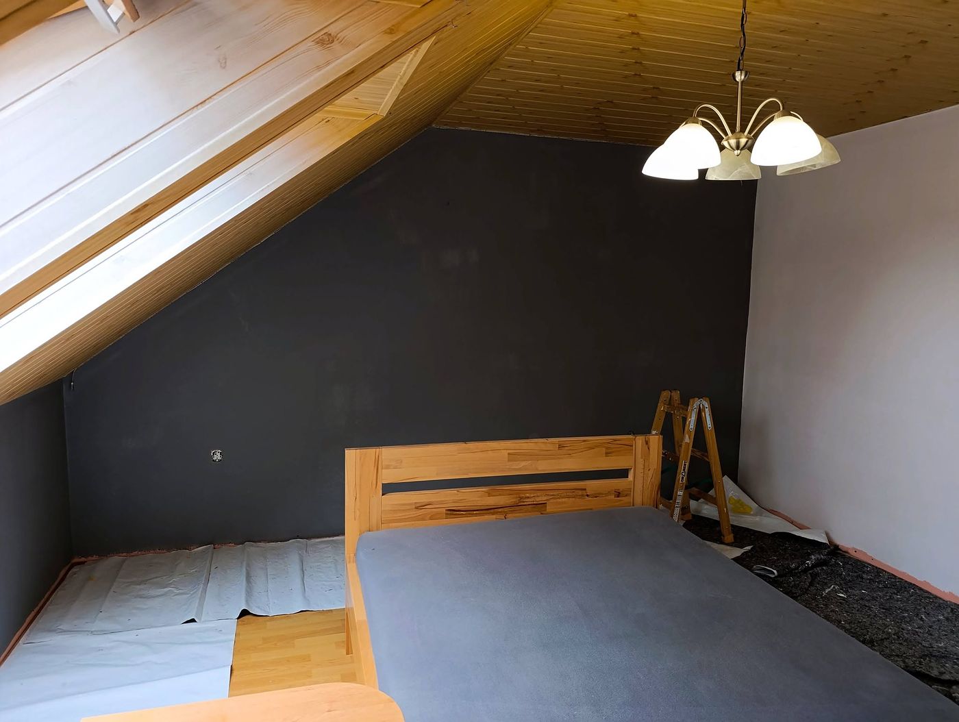 Podkrovní ložnice s nově vymalovanou antracitovou stěnou